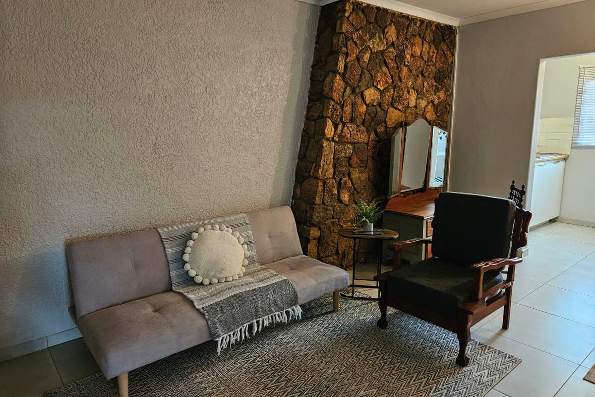 A living room featuring a prominent stone fireplace feature wall and neutral tiled flooring, offering a cozy and textured aesthetic.