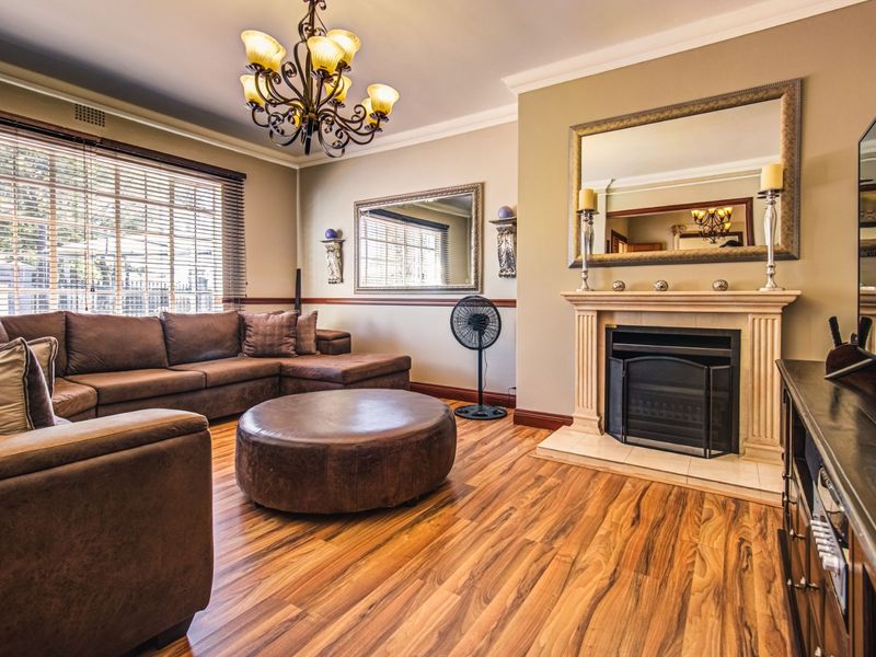 A comfortable living room featuring warm laminate flooring, a classic fireplace, and crown molding, creating a cozy and inviting atmosphere.