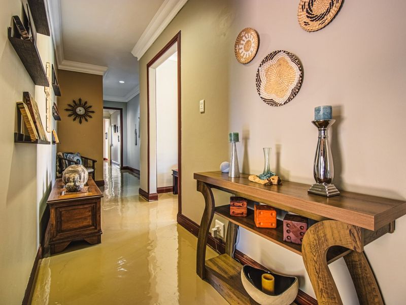 A well-maintained hallway featuring crown molding, baseboards, and recessed lighting, connecting multiple rooms within the home.