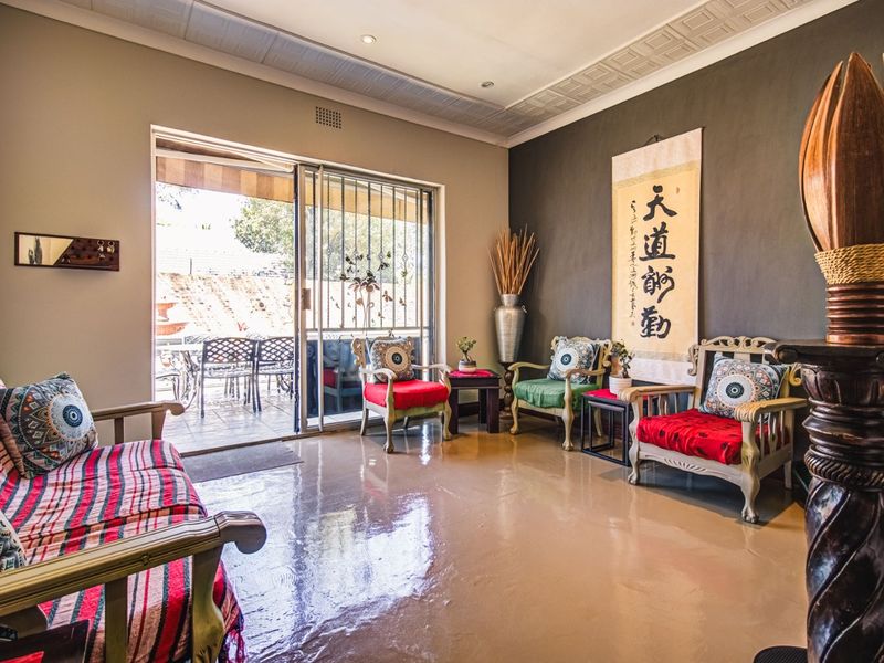 A well-lit living room featuring a coffered ceiling, recessed lighting, and large sliding glass doors that provide direct access to the outdoor patio area.