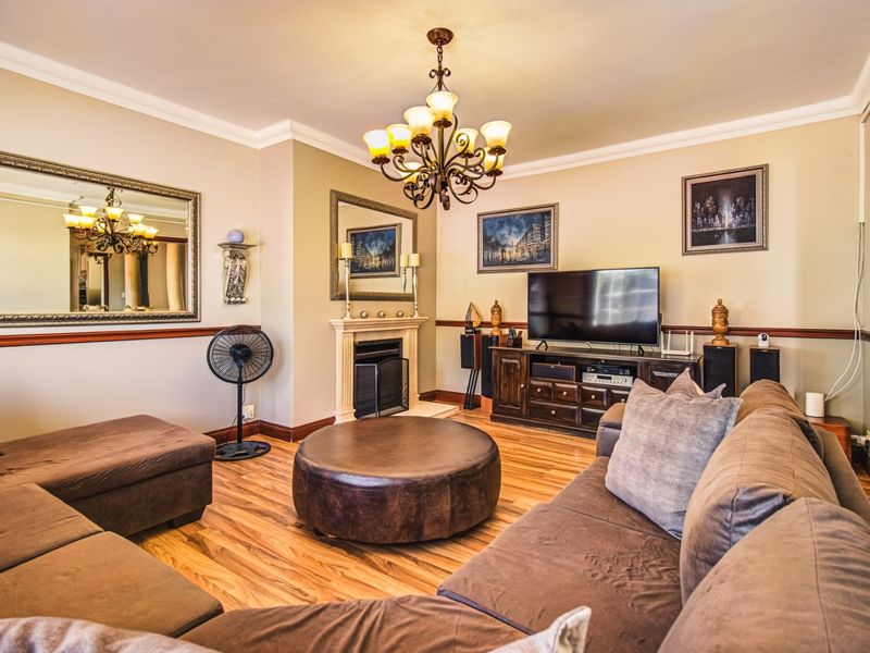 A comfortable living room featuring a fireplace with a mantelpiece, crown molding, chair rail detailing, and durable laminate flooring.