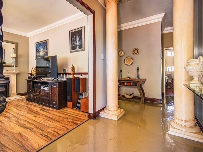 A well-maintained living area featuring decorative columns, a fireplace mantel, and laminate flooring, creating a warm and inviting atmosphere.