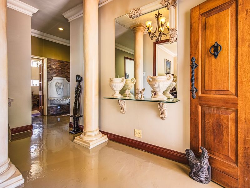 Elegant entrance hall featuring decorative columns, crown molding, a solid wood door, and a unique wall-mounted fountain feature.