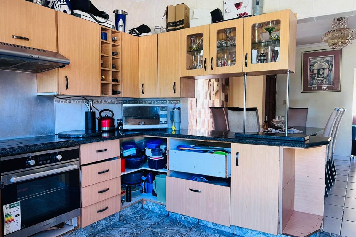 A dated kitchen featuring laminate cabinetry, granite countertops, and a built-in oven, requiring cosmetic updates to improve functionality and aesthetic appeal.