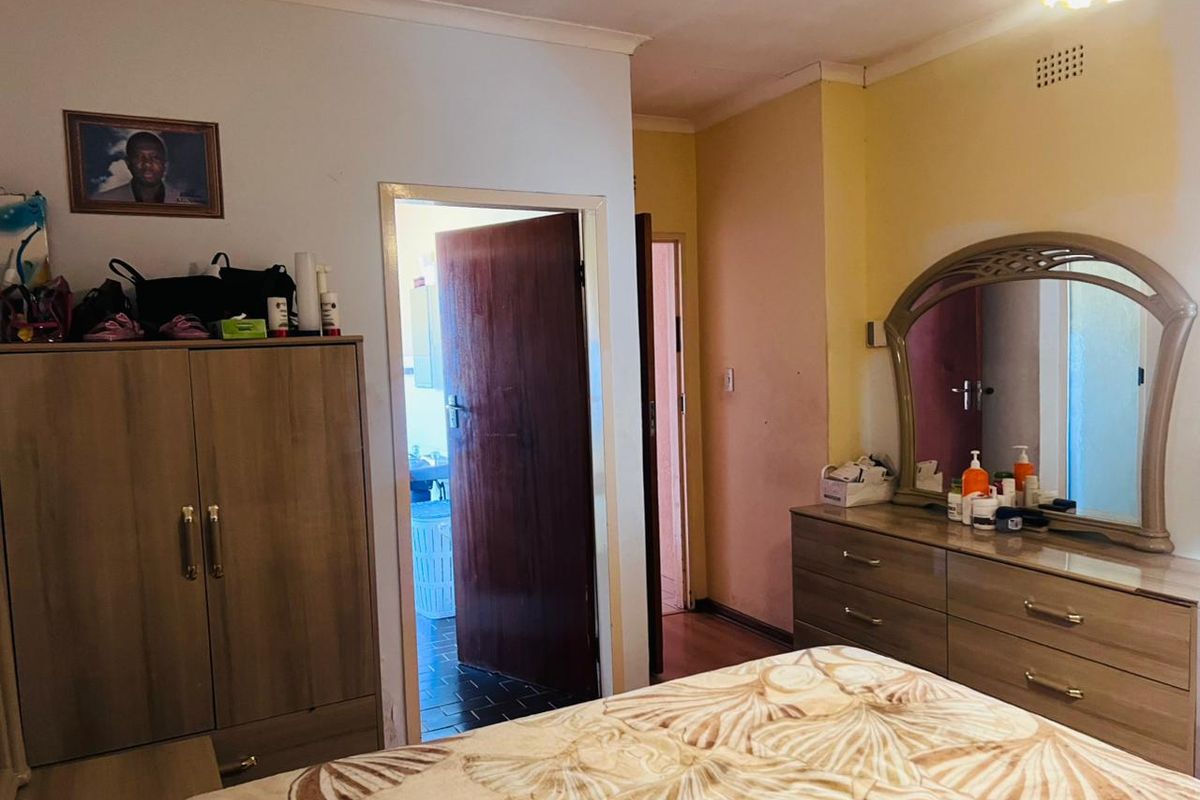 A bedroom featuring standard internal doors and coving, showing signs of wear on the wall surfaces.