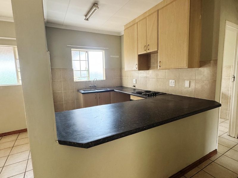 A functional kitchen featuring built-in cabinetry, laminate countertops, a breakfast bar, and ceramic tile flooring, offering a clean and practical layout.