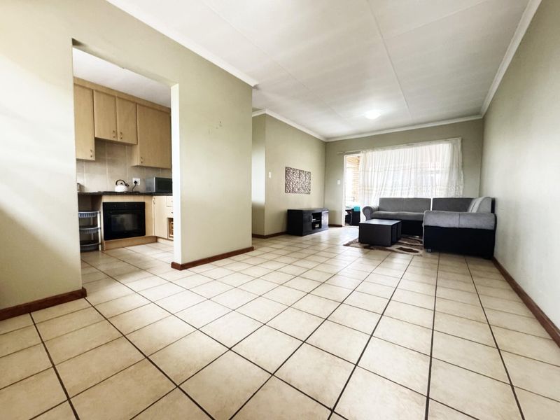 Open-plan living area featuring tiled flooring, a functional kitchen with built-in cabinetry and oven, and direct access to an outdoor space via sliding doors.