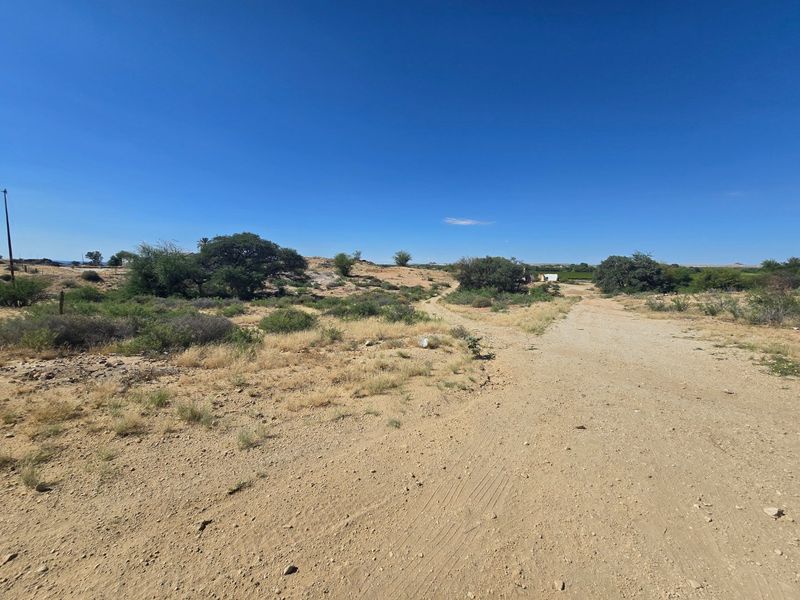 An expansive view of a commercial property site featuring a dirt access road and natural landscape.