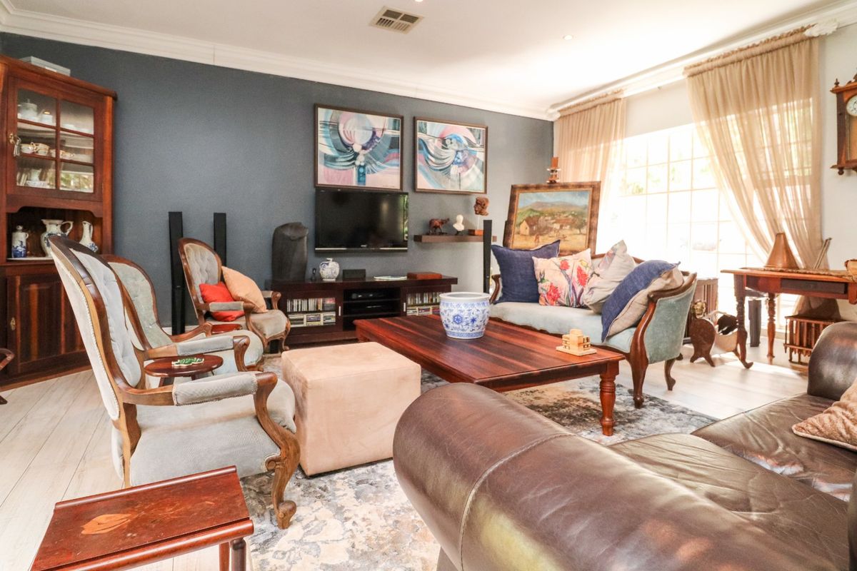 A spacious living room featuring tiled flooring, coved ceilings with recessed lighting, and a large window allowing for ample natural light.