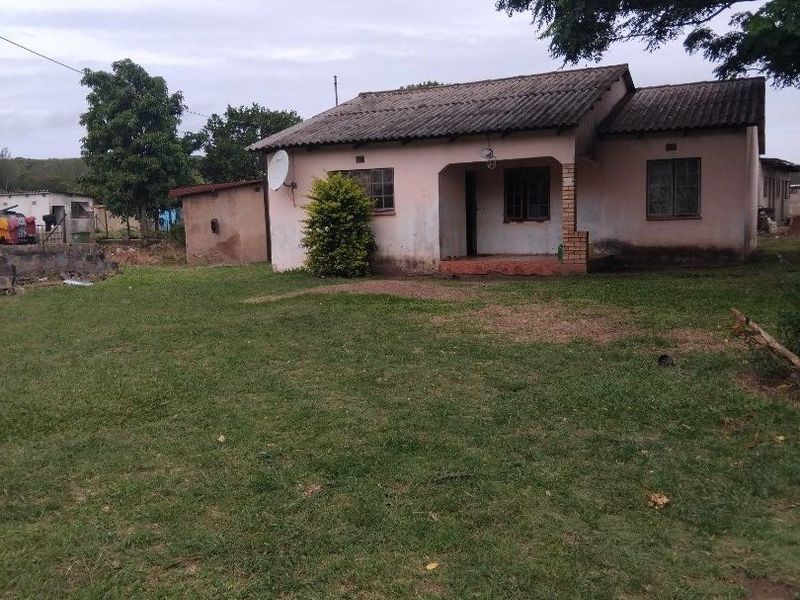 A single-story detached house featuring a tiled roof and a covered front porch, set on a large grassed plot.