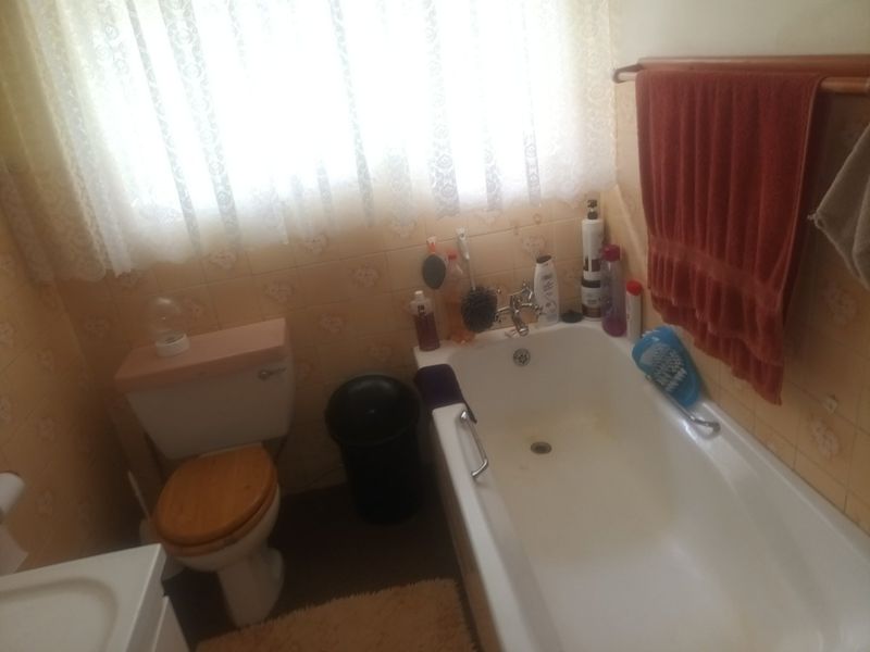 A dated bathroom featuring a standard bathtub, toilet, and wall tiling, requiring modernization to improve functionality and aesthetic appeal.
