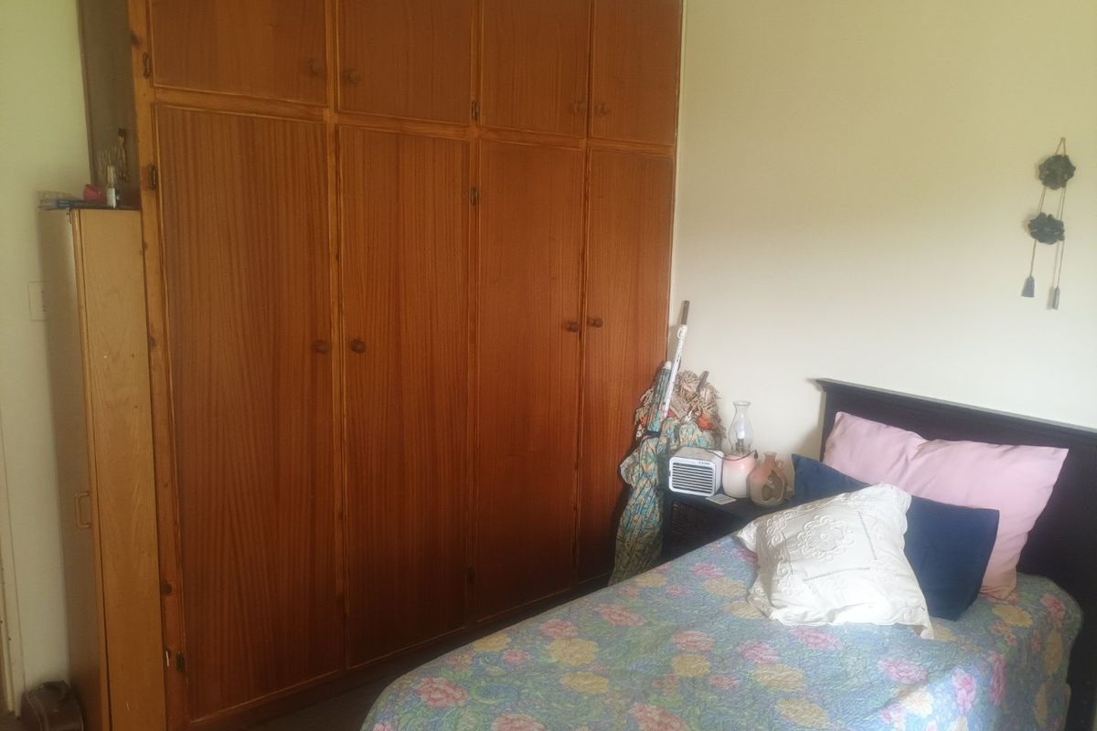 A bedroom featuring a large, floor-to-ceiling built-in wooden wardrobe providing ample storage space.