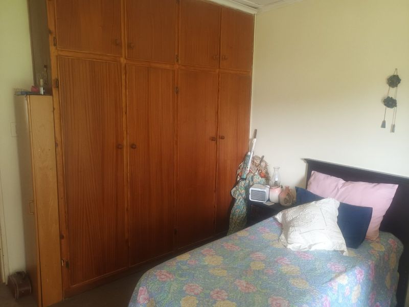 A bedroom featuring a large, floor-to-ceiling built-in wooden wardrobe providing ample storage space.