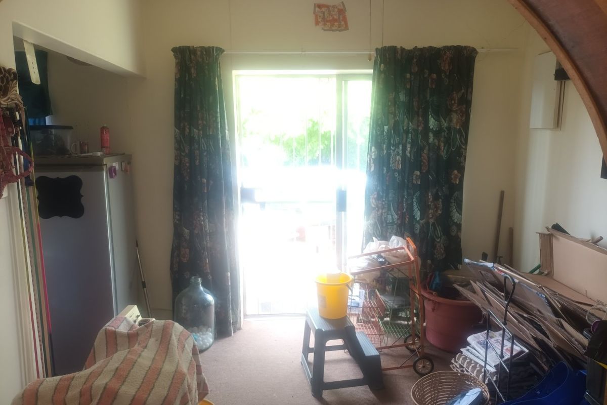 A living area featuring a sliding glass door providing access to the exterior, equipped with a ceiling fan and carpeted flooring.