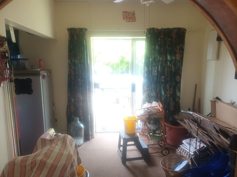 A living area featuring a sliding glass door providing access to the exterior, equipped with a ceiling fan and carpeted flooring.