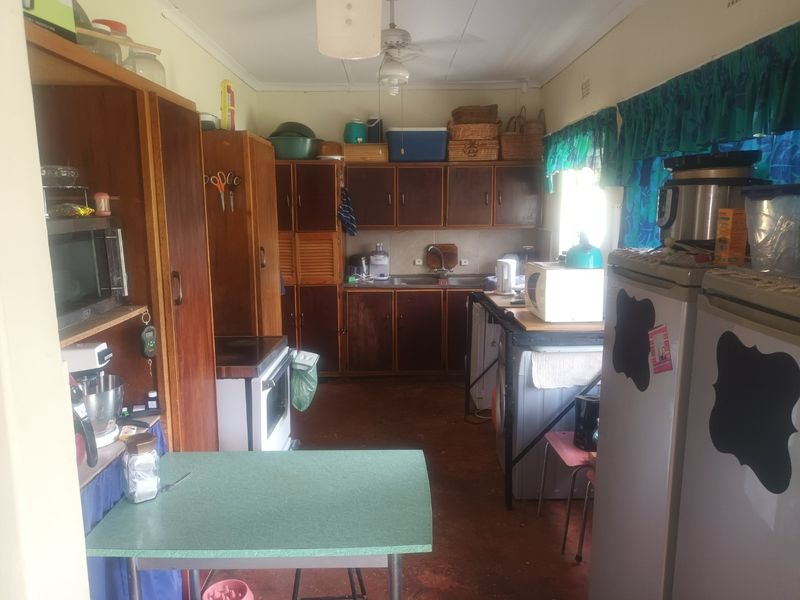 A dated kitchen featuring original wooden cabinetry, a stainless steel sink, and a freestanding oven, offering significant potential for a modern renovation.