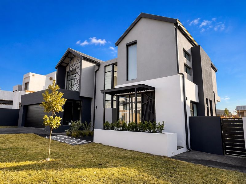 Modern double-story residential property featuring a contemporary facade, paved driveway, integrated double garage, and manicured front garden area.