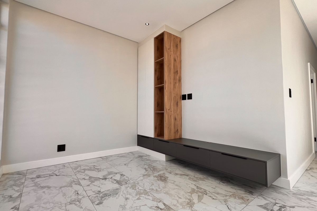 Modern living area featuring sleek built-in cabinetry, high-quality marble-look floor tiles, and clean, minimalist finishes throughout.
