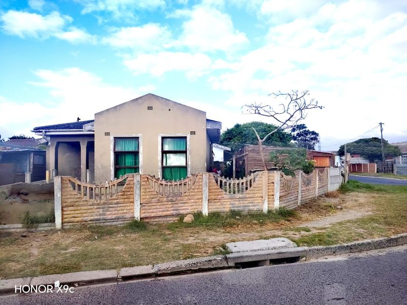 Front elevation of a single-story house featuring a precast concrete boundary wall and a tiled roof, showing signs of significant weathering and exterior wear.
