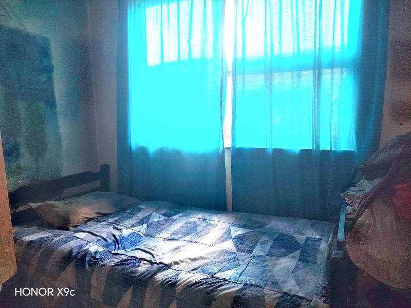 A bedroom featuring a window with blue curtains, providing natural light to the space.