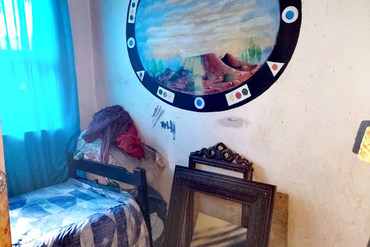 A bedroom featuring tiled flooring and a window, currently requiring cosmetic updates and wall repairs to improve the overall condition of the space.