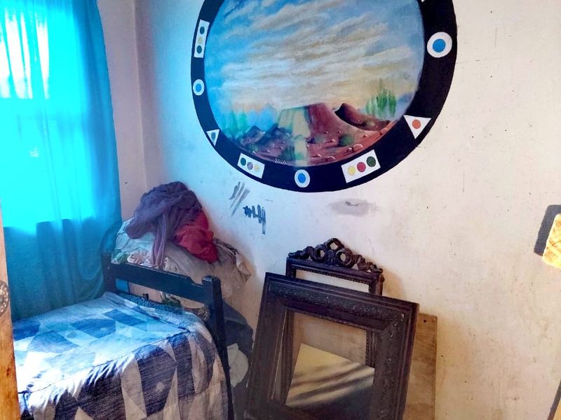 A bedroom featuring tiled flooring and a window, currently requiring cosmetic updates and wall repairs to improve the overall condition of the space.