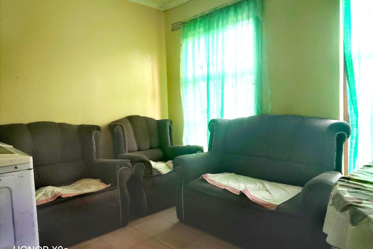 A living room area featuring tiled flooring and standard cornicing, currently requiring cosmetic updates to the wall finishes.