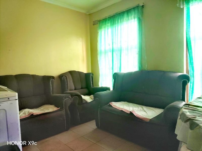 A living room area featuring tiled flooring and standard cornicing, currently requiring cosmetic updates to the wall finishes.