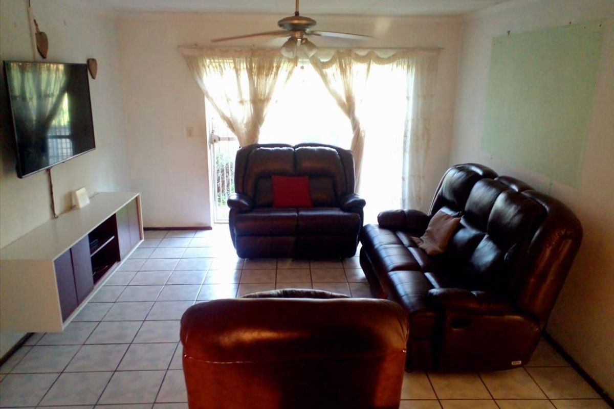 A living room featuring tiled flooring, a ceiling fan, and a sliding glass door providing access to the exterior.