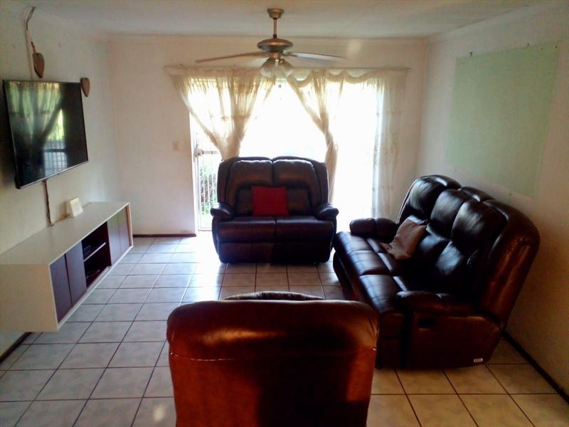 A living room featuring tiled flooring, a ceiling fan, and a sliding glass door providing access to the exterior.