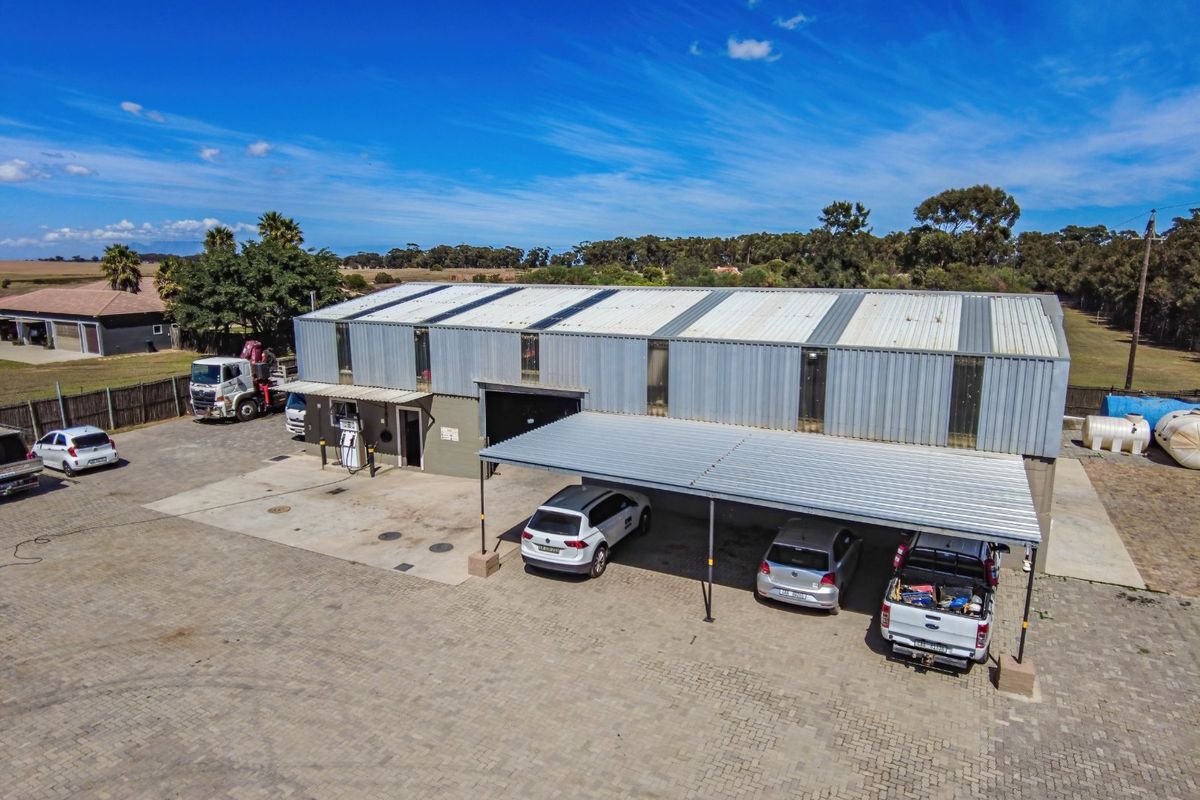 Aerial view of a large industrial-style farm building featuring a metal roof, attached carport, and an on-site fuel pump station.