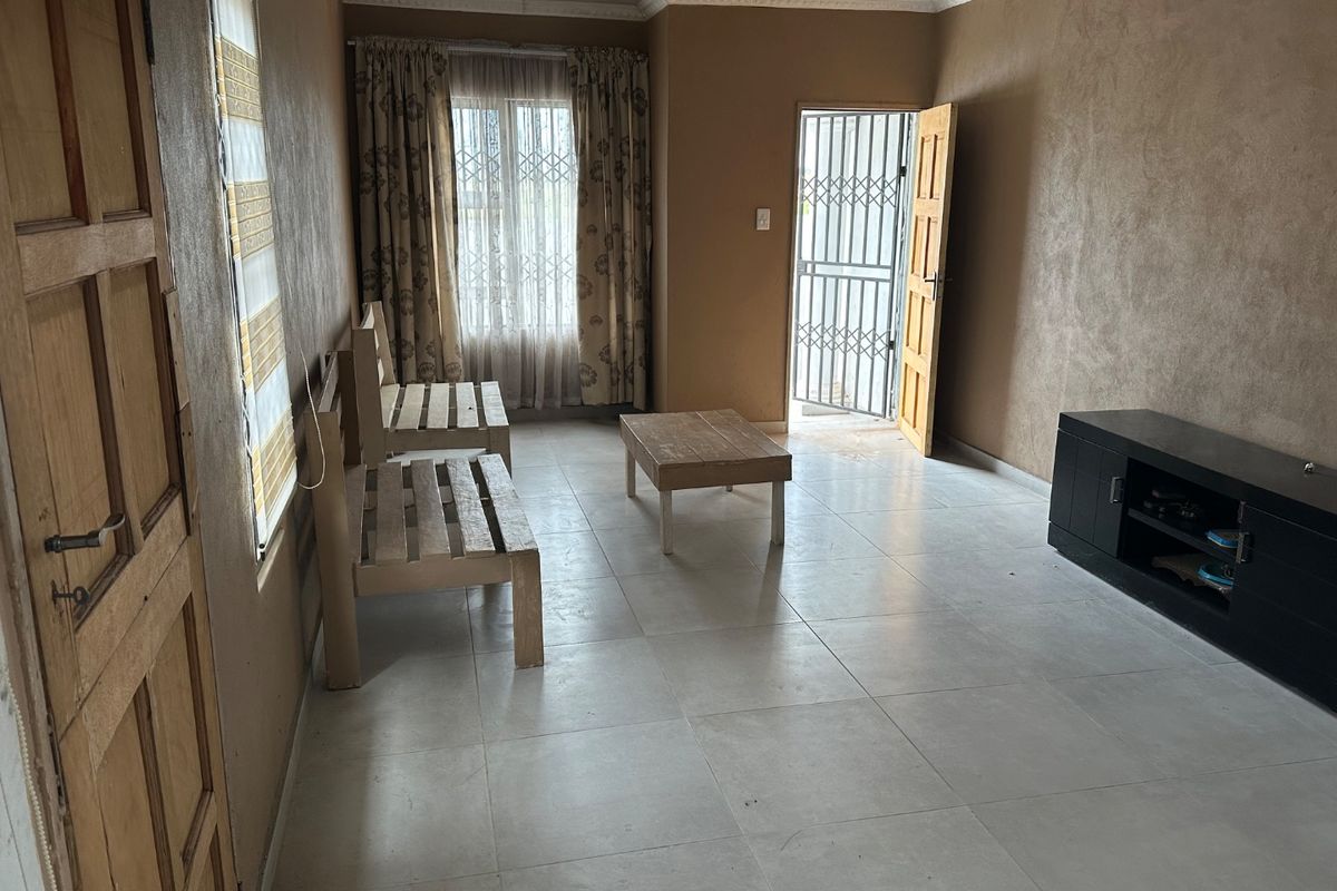 A living room featuring tiled flooring, a security gate, and timber door access, with textured walls and simple crown molding.