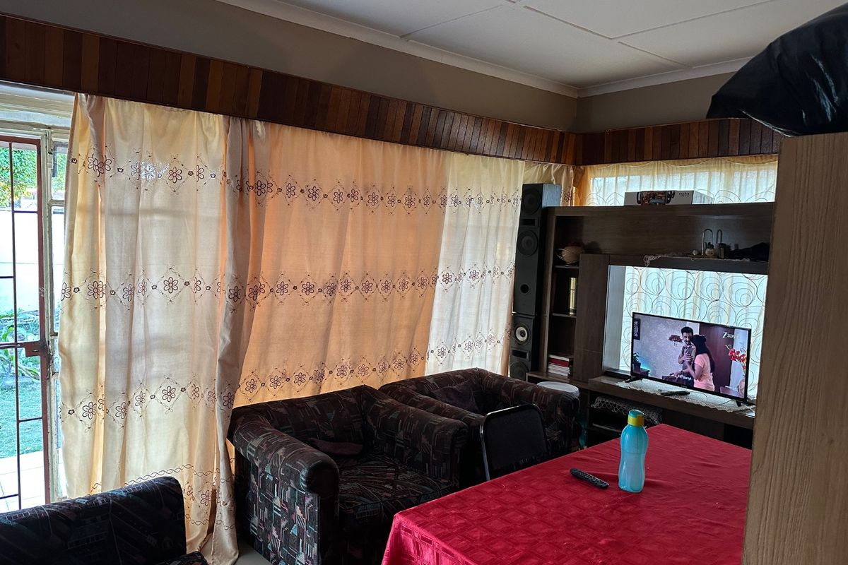 A living room featuring a timber pelmet, tiled flooring, and a sliding glass door providing access to the exterior.