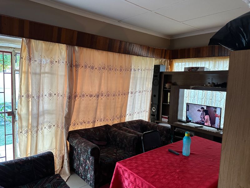 A living room featuring a timber pelmet, tiled flooring, and a sliding glass door providing access to the exterior.