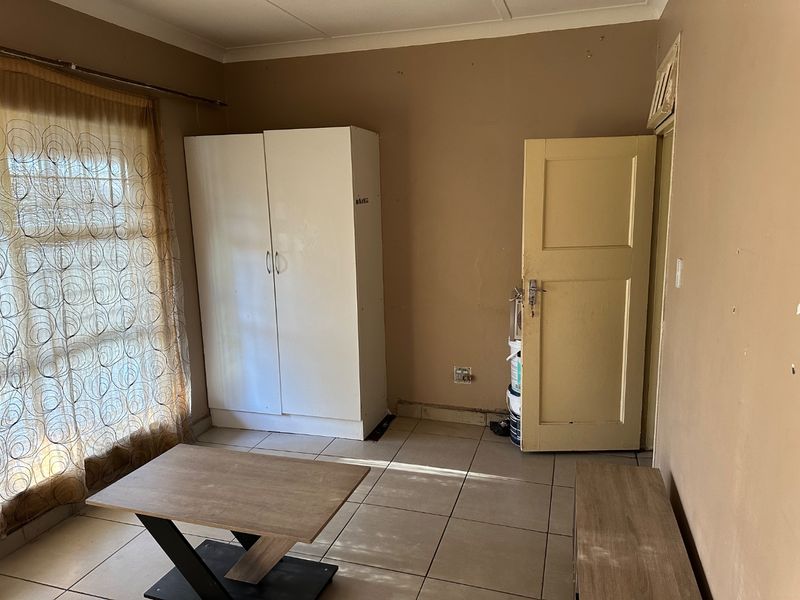 A bedroom featuring tiled flooring, a built-in wardrobe, and a neutral color palette, offering a functional space ready for cosmetic updates.