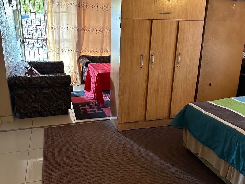 A bedroom featuring tiled flooring, a ceiling fan, and direct access to an outdoor area through a security gate.