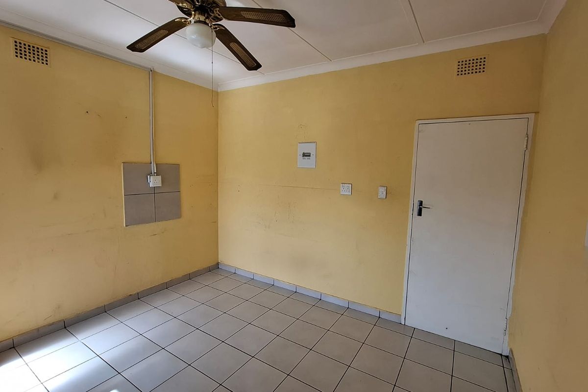 An empty bedroom featuring tiled flooring, a ceiling fan, and dated wall finishes, presenting a blank canvas for renovation or cosmetic updates.