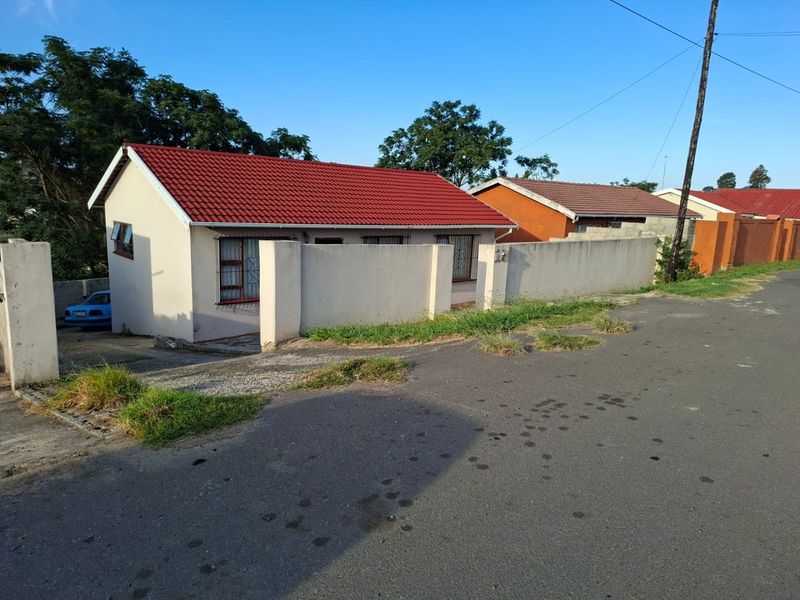 Front exterior view of a single-story house featuring a red tiled roof, perimeter wall with security bars, and a paved driveway.