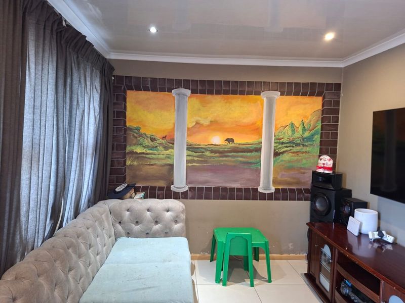 A living room featuring tiled flooring, recessed downlighting, and a decorative mural on the feature wall.