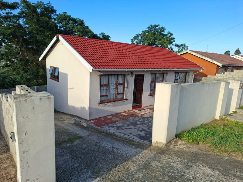 Front view of a detached house featuring a red tiled roof, security bars on windows, and a concrete boundary wall with a driveway.
