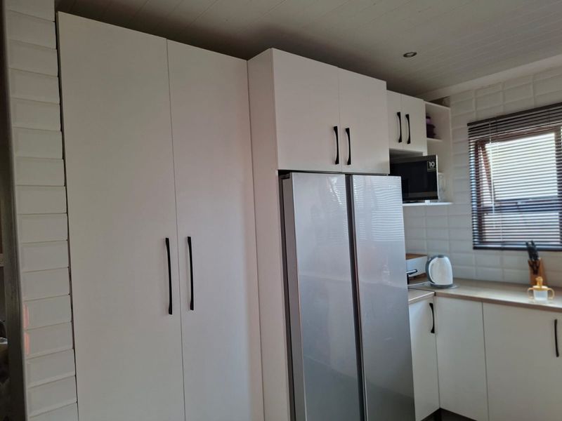 Modern kitchen featuring white cabinetry, subway tile backsplash, and integrated microwave, offering a clean and functional workspace.