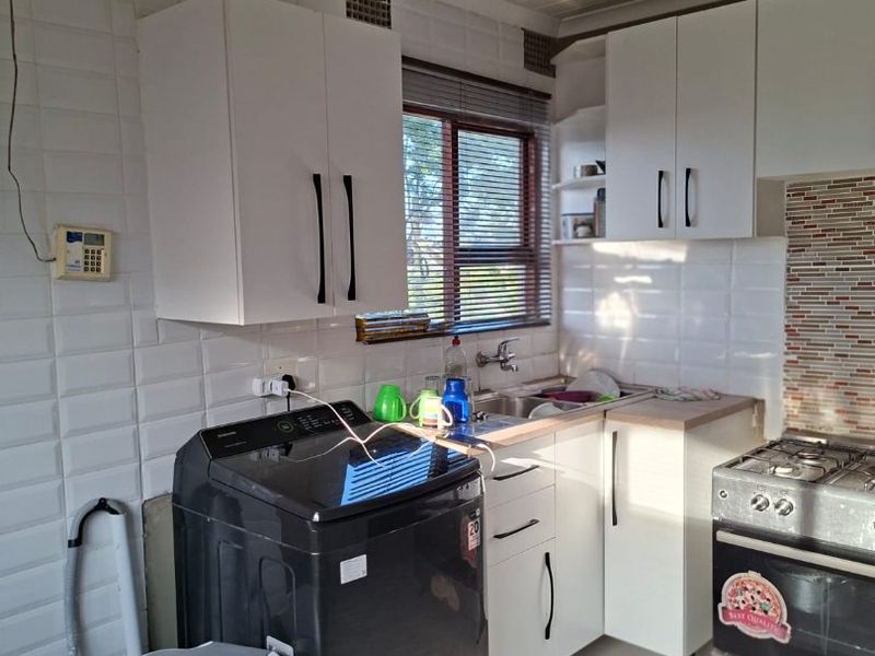 A functional kitchen featuring white cabinetry, subway tile backsplash, stainless steel sink, and a gas stove with tiled flooring.