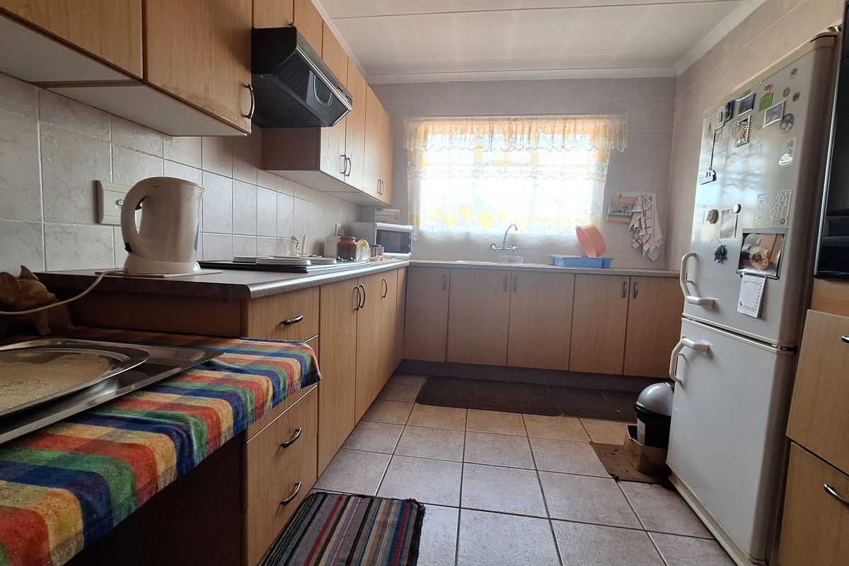 A functional kitchen featuring laminate cabinetry, tiled backsplash, and tiled flooring, offering a practical layout with built-in storage and workspace.