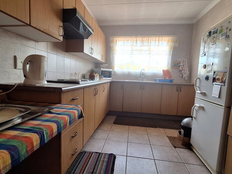 A functional kitchen featuring laminate cabinetry, tiled backsplash, and tiled flooring, offering a practical layout with built-in storage and workspace.