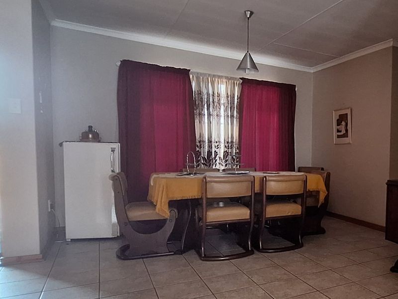 A functional dining area featuring tiled flooring, coved ceilings, and a central pendant light fixture, providing a practical space for family meals.