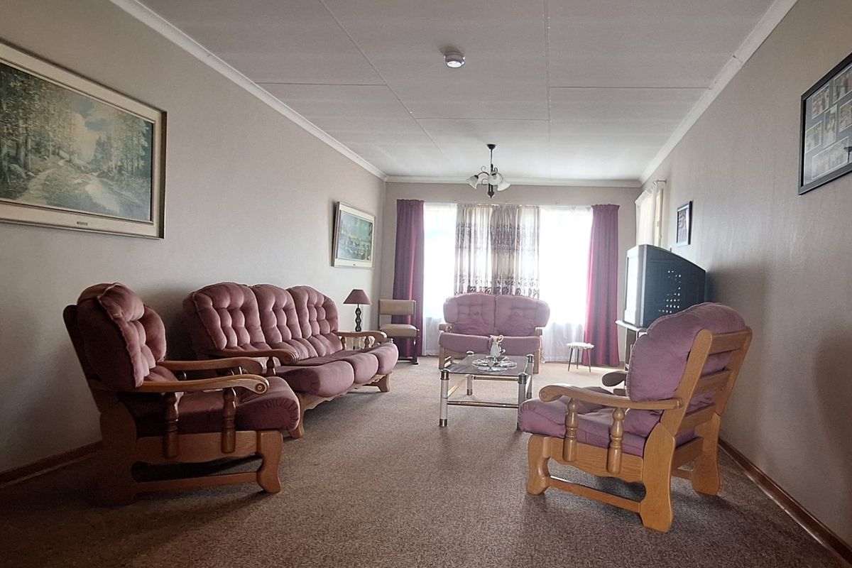 A spacious living room featuring neutral wall tones, carpeted flooring, and classic coving, offering a comfortable and functional layout for relaxation.