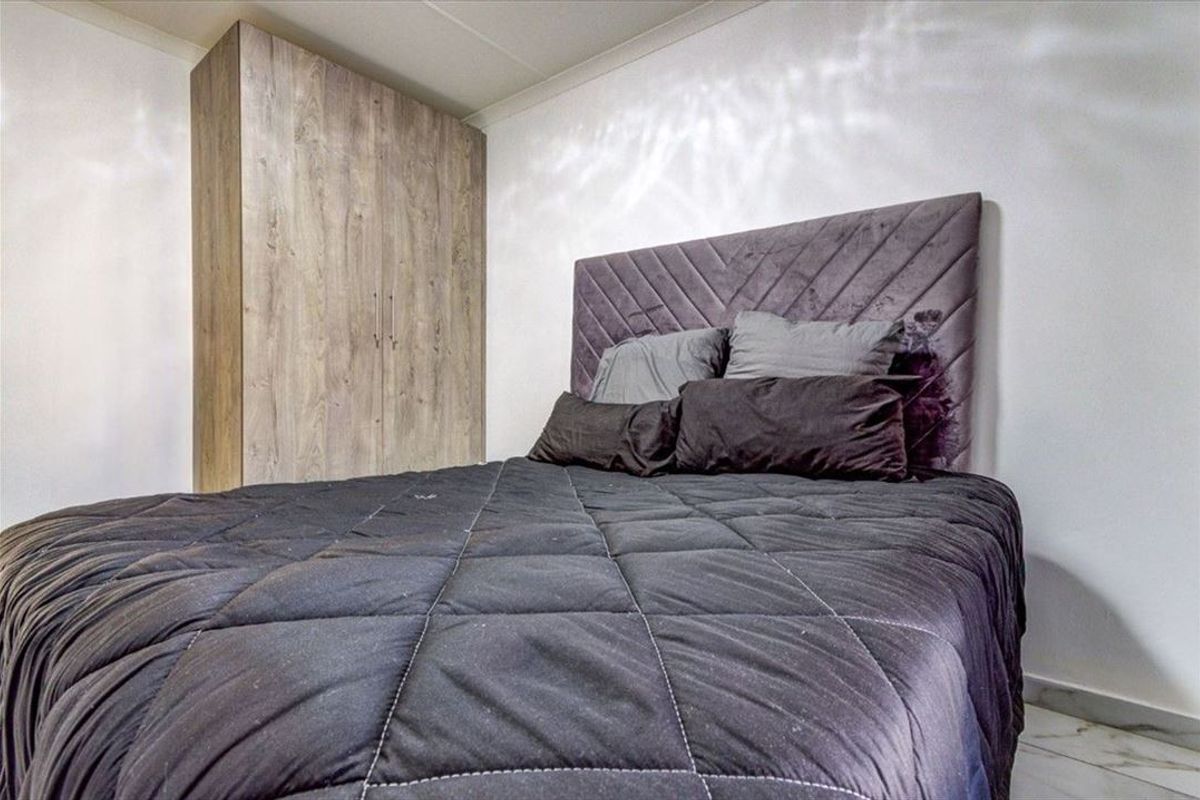A bedroom featuring a built-in wardrobe with a wood-grain finish and coved ceiling detailing.