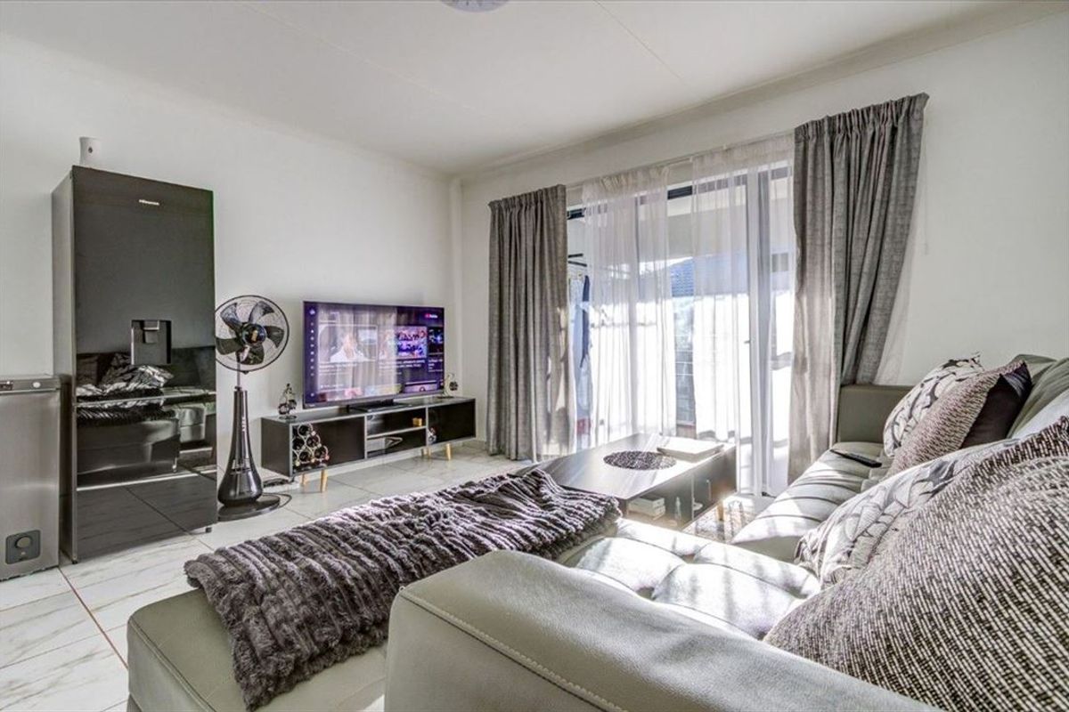 A bright living room featuring tiled flooring and a large sliding glass door that provides access to the exterior.