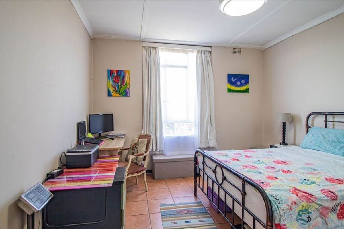A bedroom featuring tiled flooring and a central window, requiring cosmetic updates to the wall and ceiling finishes to improve its overall condition.
