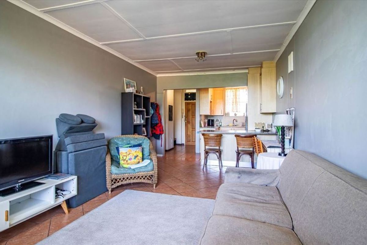 Open plan living area featuring tiled flooring and a functional kitchen with breakfast bar, providing a versatile space for daily living.